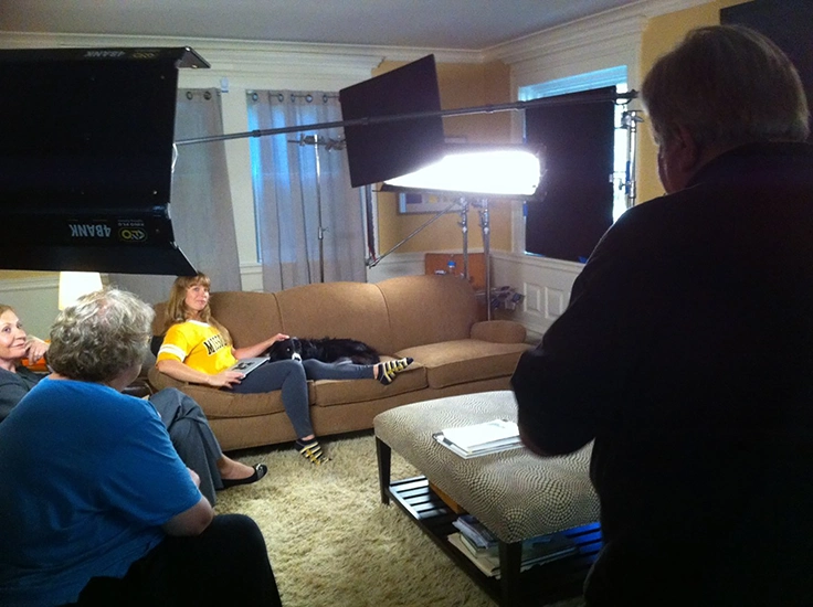 Wide angle image of lights and set for video shooting with Border Collie on lap of young woman