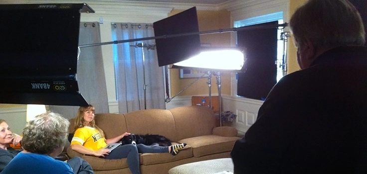 Wide angle image of lights and set for video shooting with Border Collie on lap of young woman